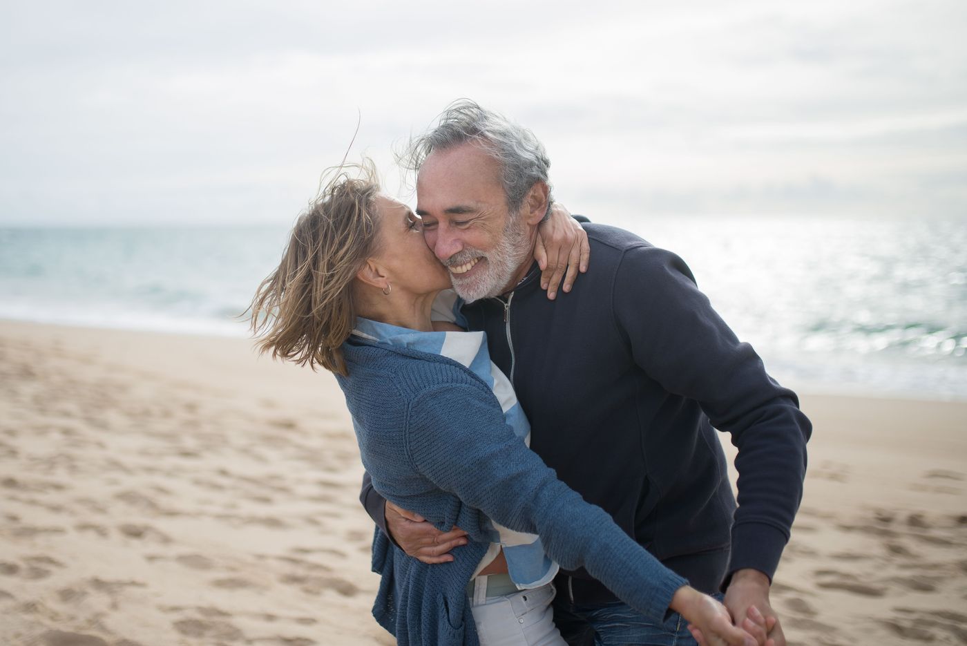 Joyful mature couple embracing on a breezy beach